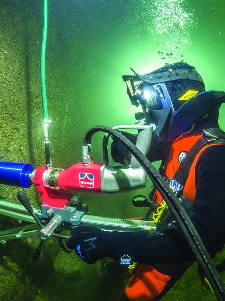 Taucher verwendet hydraulischen Steinbohrer von HYCON bei der Arbeit unter Wasser, umgeben von Felsen